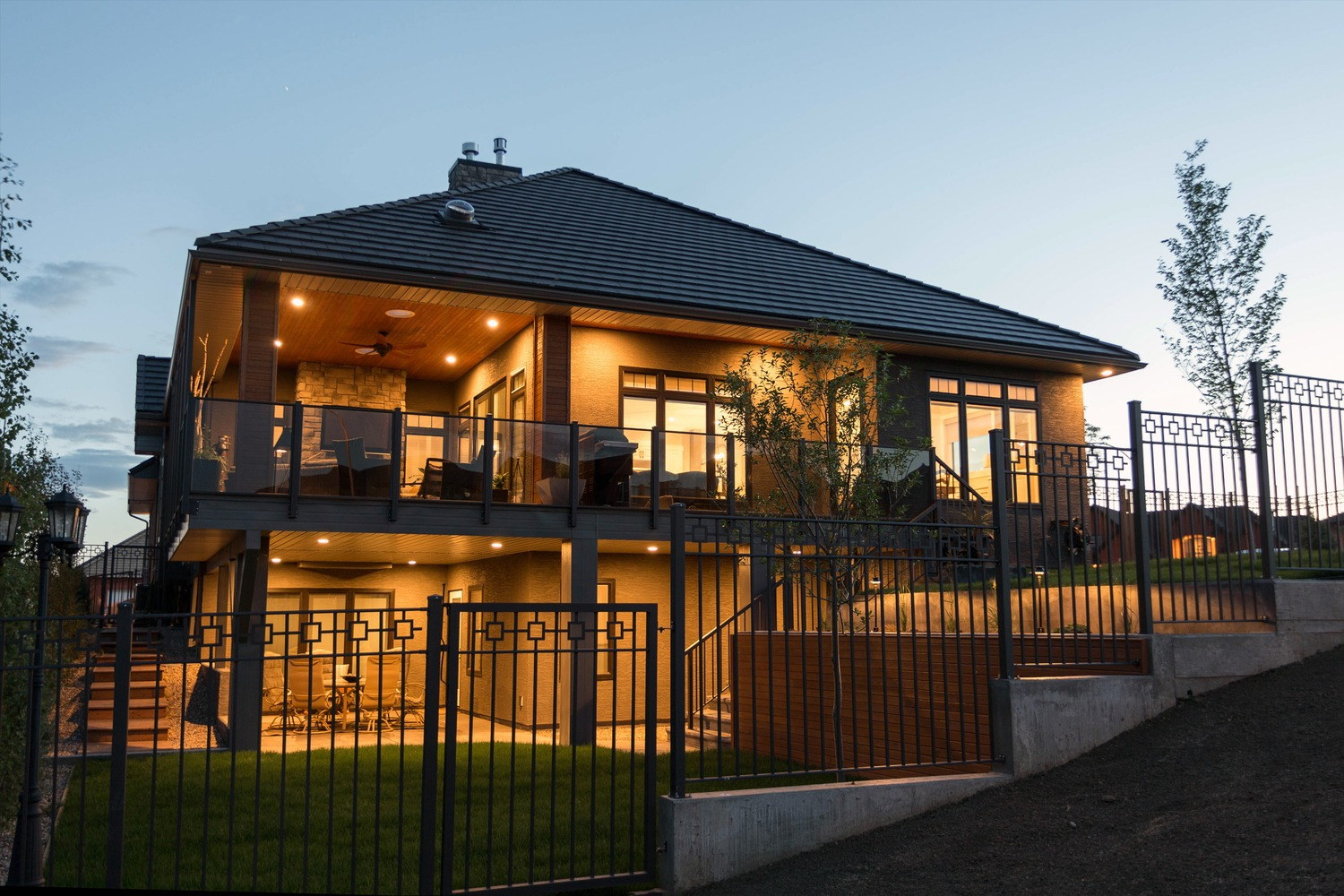 Covered walkout outdoor living areas with glass railings and integrated exterior lighting.