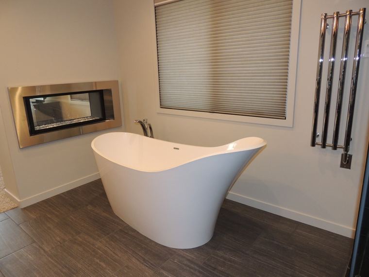 Spa-style bathroom with a sculptural freestanding tub, linear fireplace and wall-mounted heated towel rack.