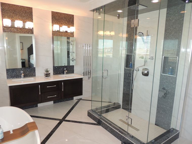 Luxury primary ensuite with a double vanity, integrated storage, glass shower, soaker tub and marble-look tile.