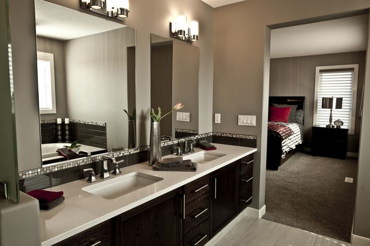 Primary ensuite with a dark wood double vanity, large mirrors and a direct connection to the bedroom.