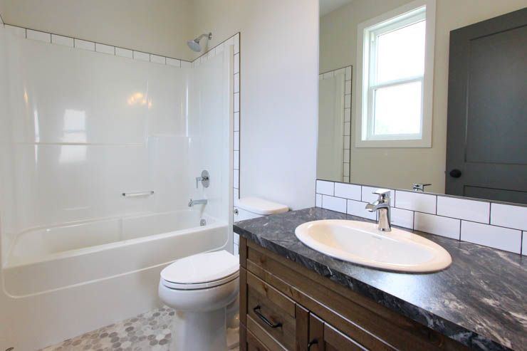 The Brant — finished bathroom with dark wood vanity and tiled details