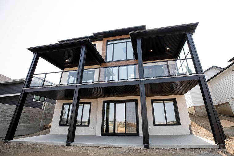 Contemporary two-storey custom home with covered upper and lower outdoor living areas.