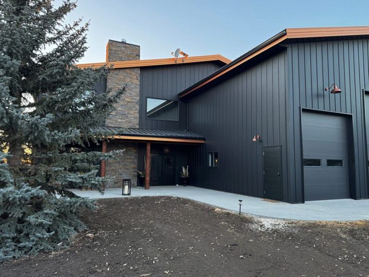 Custom Barndominium — covered entrance, stone chimney and durable metal exterior