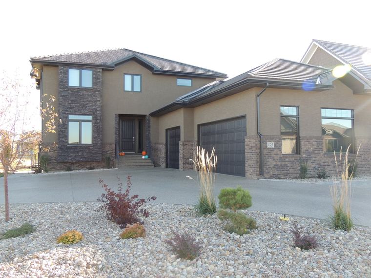 Luxury stucco and brick custom home with integrated garages and low-maintenance landscaping.