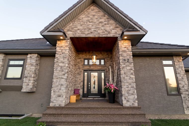 Stone-clad custom bungalow entry with a deep covered porch and detailed front door.