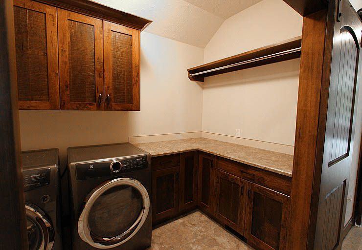 Custom Cabin — laundry and utility space with custom wood cabinetry and folding counter