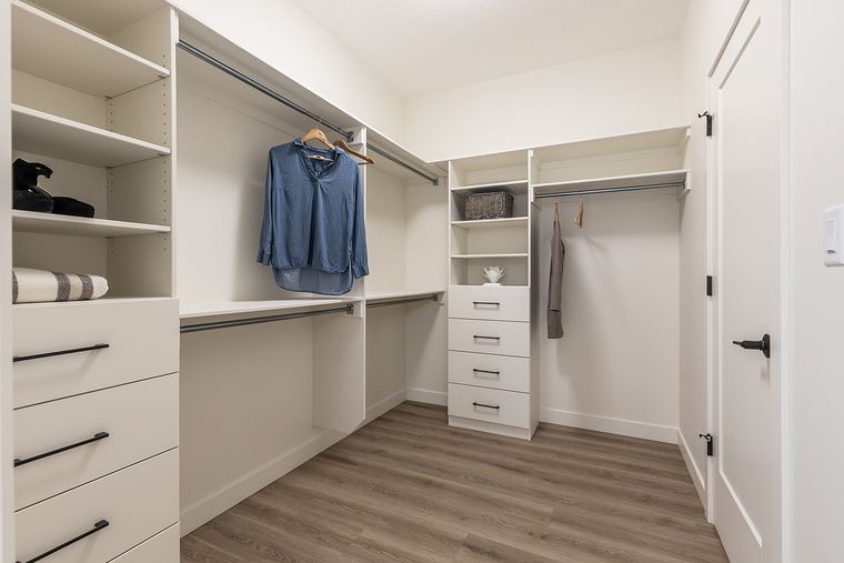 Custom walk-in closet with adjustable shelving, integrated drawers and multiple hanging zones for organized everyday storage.