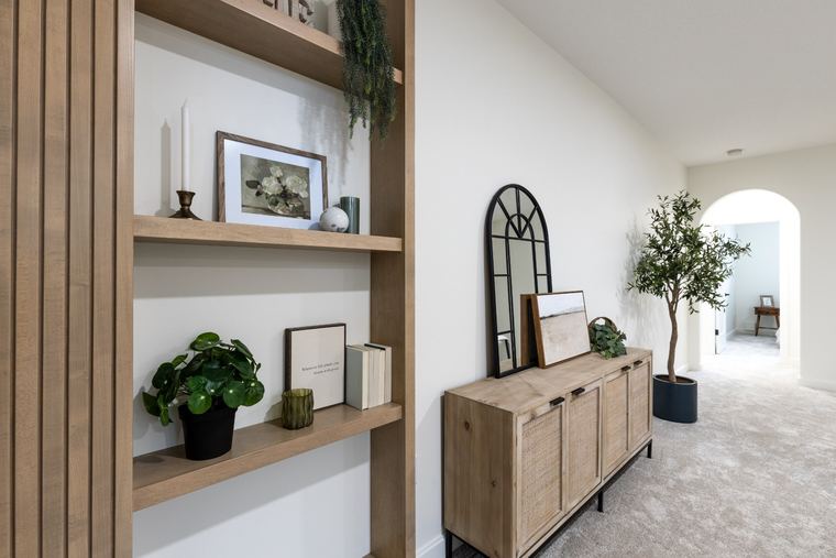 Upper hallway with custom built-in wood shelving, a coordinated console, soft carpeting and an arched doorway.