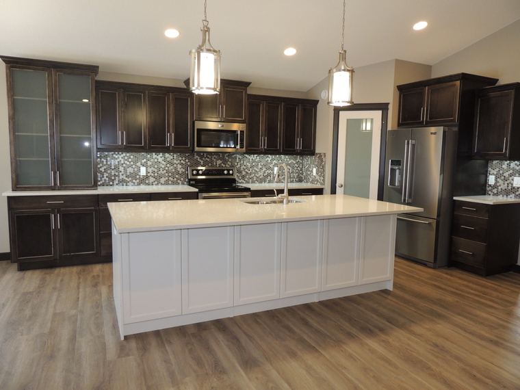 Custom kitchen with dark wood cabinetry, a contrasting white quartz island, mosaic backsplash and stainless-steel appliances.