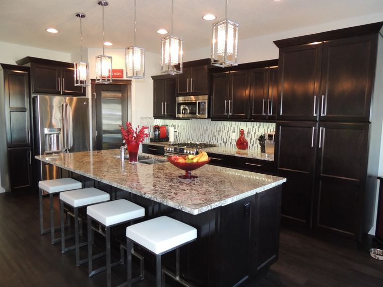Large custom kitchen with espresso cabinetry, a granite island, stainless-steel appliances and five statement pendant lights.