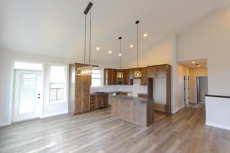 The Brant — open kitchen with custom wood cabinetry and connection to the vaulted living area
