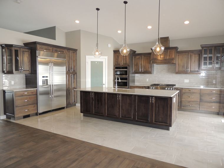 Rustic custom kitchen with two-tone wood cabinetry, an oversized island, glass display doors and polished tile flooring.