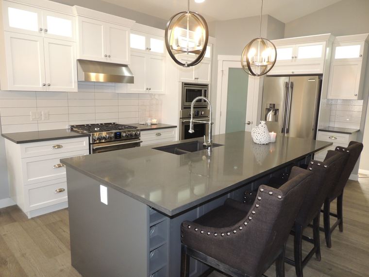 White custom kitchen with full-height cabinetry, a grey quartz island, professional gas range and oversized orb pendant lights.