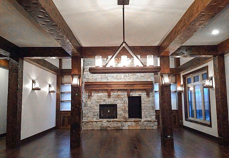 Custom Cabin — two-storey stone fireplace framed by substantial timber beams