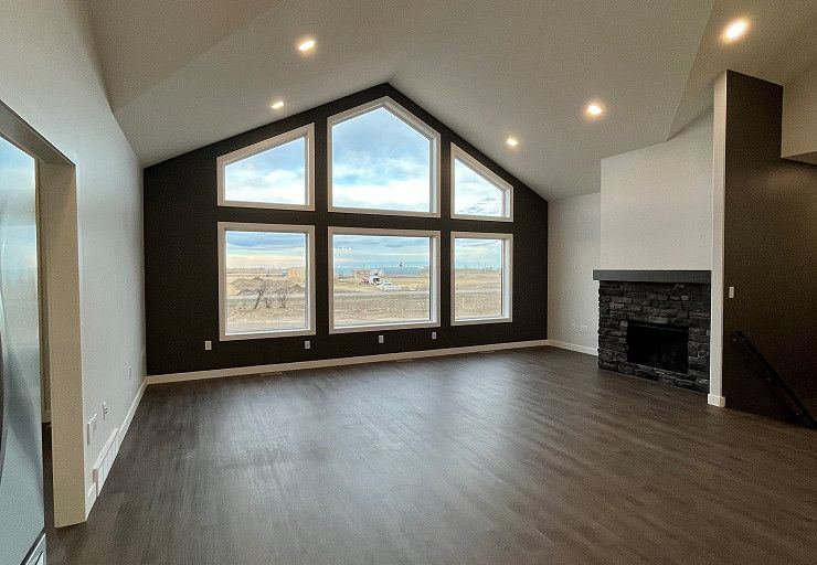 Custom Everest I Prairie Edition — vaulted great room with dramatic window wall and stone fireplace