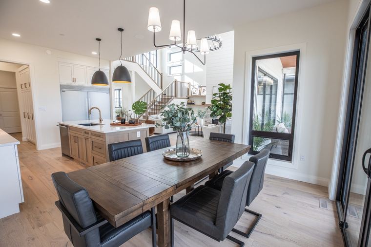 Spacious dining area connected to a bright kitchen and living room, with large windows and contemporary stair detailing.