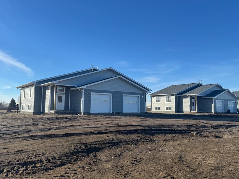 Completed duplex rental homes with attached garages and coordinated exterior finishes.
