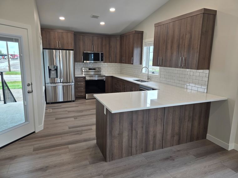 Purpose-built rental suite kitchen with dark wood cabinetry, quartz counters and stainless-steel appliances.