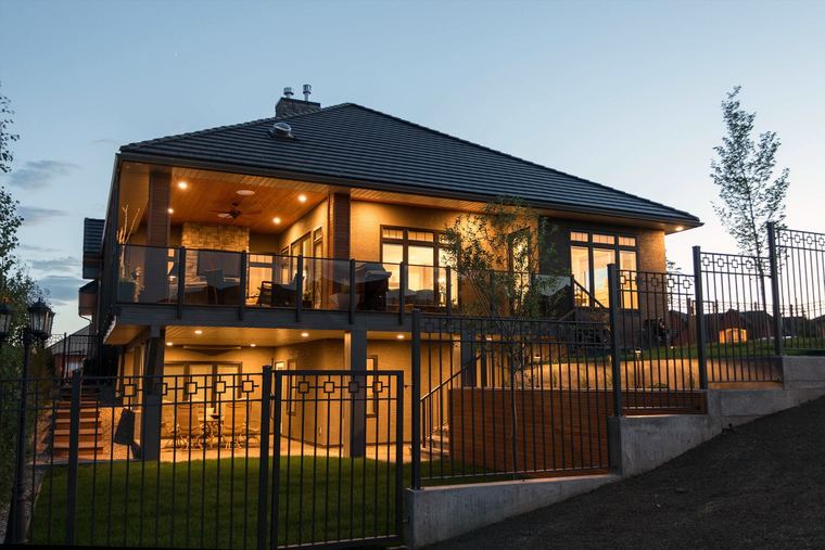 Covered walkout outdoor living areas with glass railings and integrated exterior lighting.
