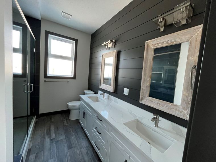 RTM home — primary ensuite with double vanity, black shiplap feature wall and glass shower