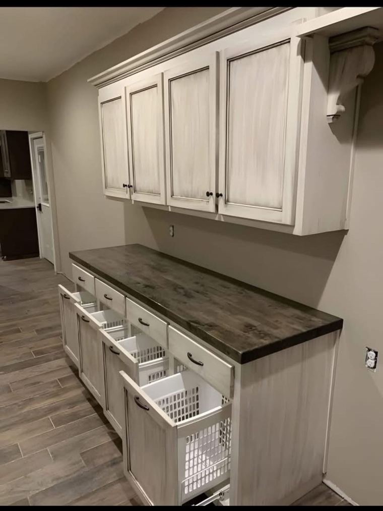 RTM home — laundry storage wall with pull-out hampers, upper cabinetry and durable work surface