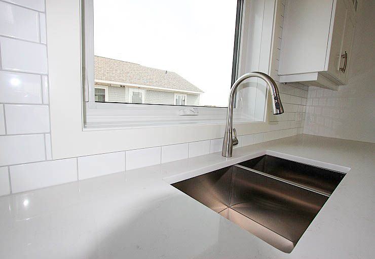 Custom Mankota I RTM — quartz kitchen surface, undermount sink and tiled backsplash detail